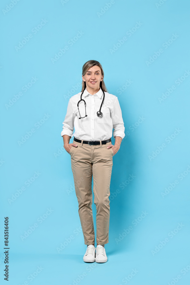 Portrait of happy doctor with stethoscope on light blue background Portrait of happy doctor with stethoscope on light blue background
