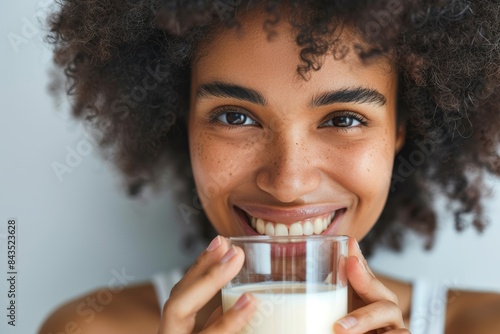 Studio portrait of woman with milk glass for healthy diet, detox, or calcium on white background. Positive African model, vanilla milkshake smoothie for weight loss, nutrition, and beauty
