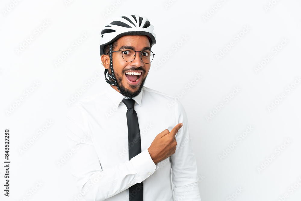 Young business latin man holding a bike helmet isolated on white background surprised and pointing side Young business latin man holding a bike helmet isolated on white background surprised and pointing side