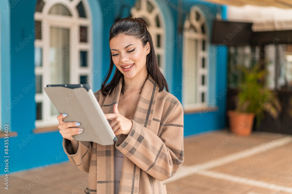 Young pretty woman at outdoors touching the tablet screen with happy expression Young pretty woman at outdoors touching the tablet screen with happy expression