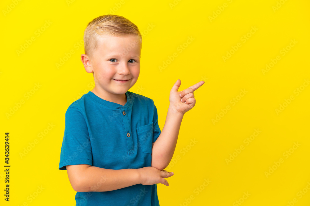Little Russian boy isolated on yellow background pointing finger to the side Little Russian boy isolated on yellow background pointing finger to the side