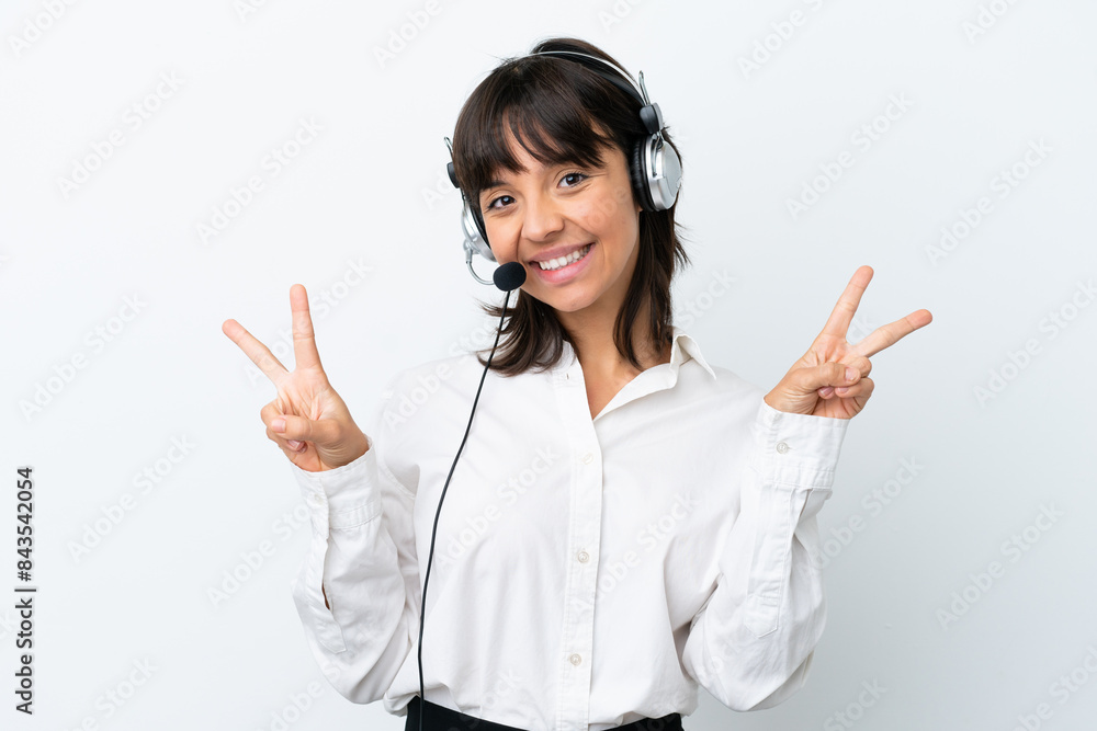 Telemarketer mixed race woman working with a headset isolated on white background showing victory sign with both hands Telemarketer mixed race woman working with a headset isolated on white background showing victory sign with both hands
