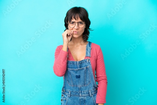 Young woman with overalls isolated background showing a sign of silence gesture