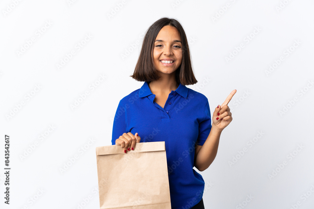 Young latin woman holding a grocery shopping bag isolated on white background pointing up a great idea Young latin woman holding a grocery shopping bag isolated on white background pointing up a great idea