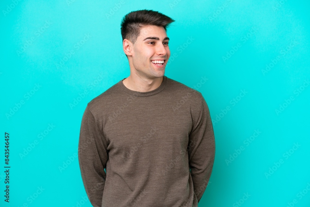 Young caucasian man isolated on blue background looking to the side and smiling Young caucasian man isolated on blue background looking to the side and smiling