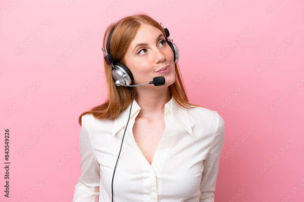 Telemarketer redhead woman working with a headset isolated on pink background and looking up Telemarketer redhead woman working with a headset isolated on pink background and looking up