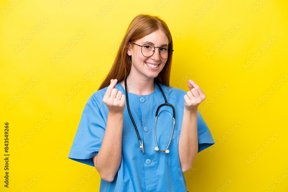 Young redhead nurse woman isolated on yellow background making money gesture Young redhead nurse woman isolated on yellow background making money gesture