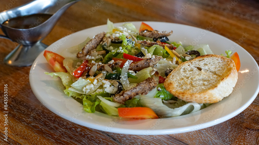 Close up of vegetable salad with beef olives, cheese and slice of bread on a white plate Close up of vegetable salad with beef olives, cheese and slice of bread on a white plate