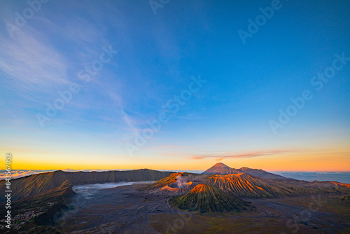 Bright morning colors on the horizon..The sun shines brightly over the sea of ​​mist at Bromo Volcano, Indonesia. At the top of the steep mountain you can see a volcanic crater and a sea of ​​mist.