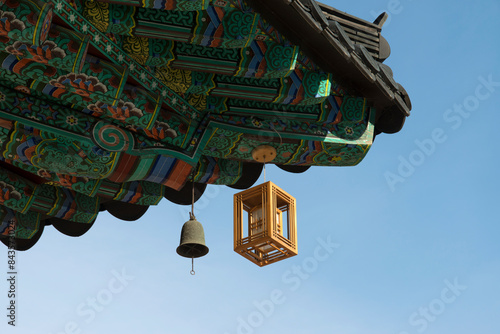 View of the lantern and bell hanging from the wooden eaves of the Buddhist temple building