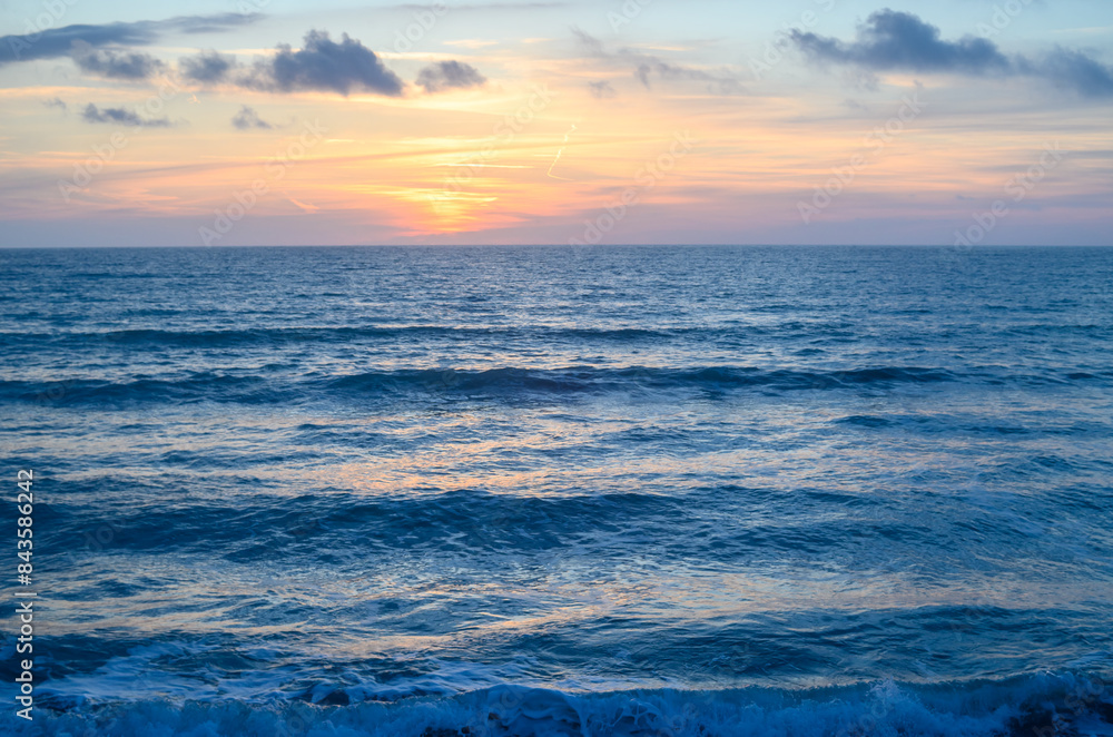 Fototapeta premium Rocky shoreline bathed in the warm glow of sunset providing a scenic view with copy space image
