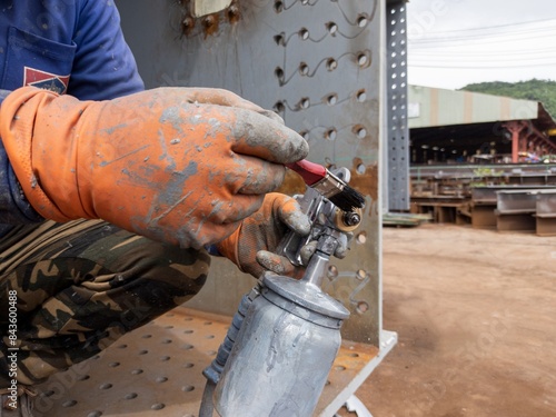 A painter is cleaning a paint spray gun using a brush dipped in thinner