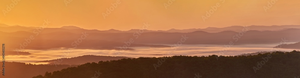 A panorama of a mountain valley in the morning mist. Picturesque dawn in the summer mountains. Warm sunlight A panorama of a mountain valley in the morning mist. Picturesque dawn in the summer mountains. Warm sunlight