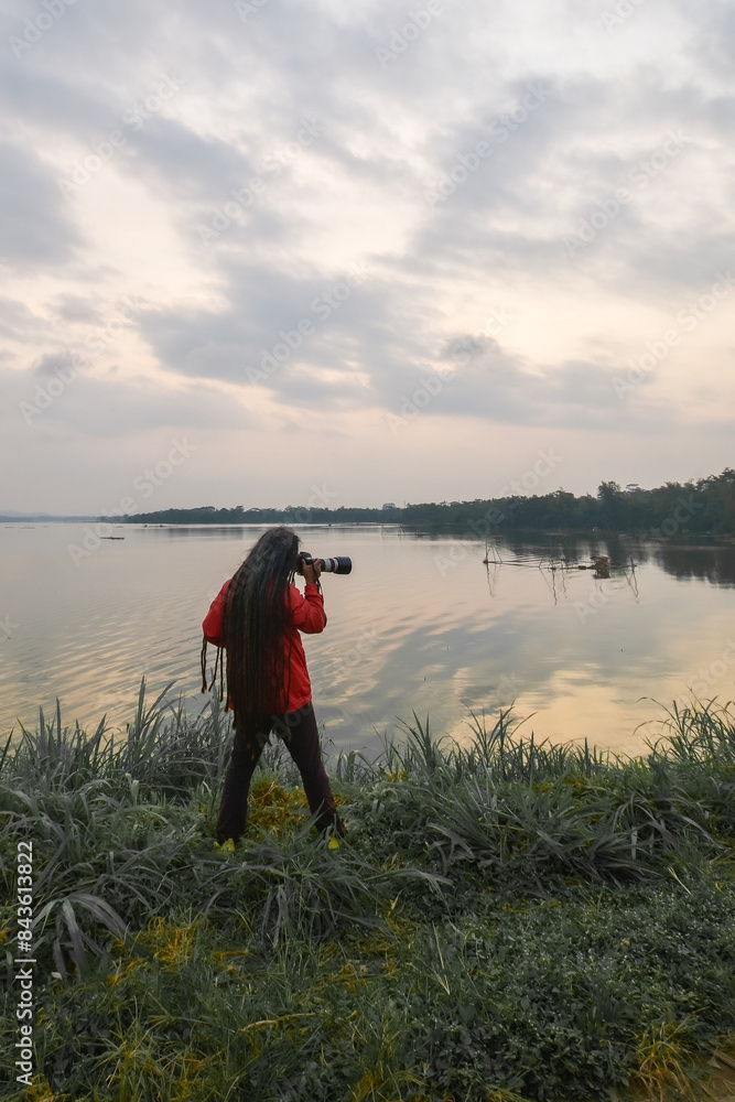 The photographer is waiting for the sunset in the photo from behind The photographer is waiting for the sunset in the photo from behind