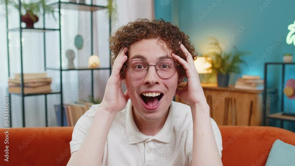 Oh my God, Wow. Young Caucasian man surprised looking at camera with big eyes, shocked by sudden victory, good win news, celebrating. Portrait of excited amazed guy at home apartment room on sofa. Oh my God, Wow. Young Caucasian man surprised looking at camera with big eyes, shocked by sudden victory, good win news, celebrating. Portrait of excited amazed guy at home apartment room on sofa.