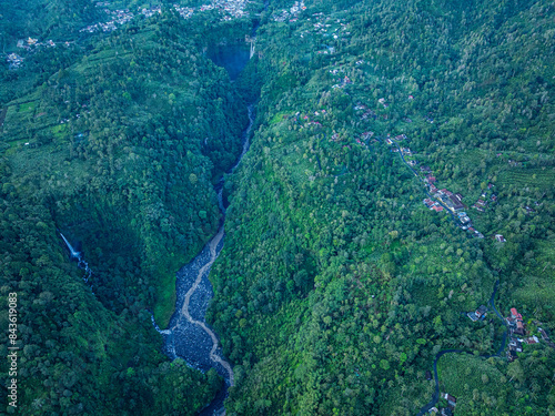 Aerial view Kabut Pelangi Waterfall in East Java. The waterfall crashes down into the amphitheater below, which is covered in lush green plants. Above is the residence of the villagers. photo