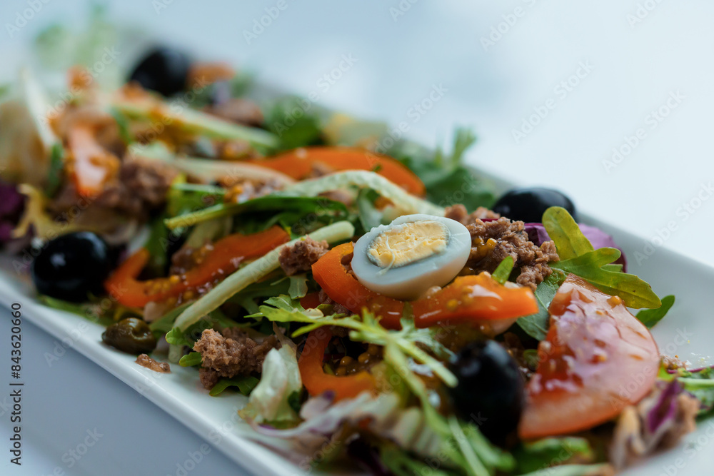 Salad with cabbage, cucumber, egg, onion, tuna and olive oil on a white saucer on a white background Salad with cabbage, cucumber, egg, onion, tuna and olive oil on a white saucer on a white background