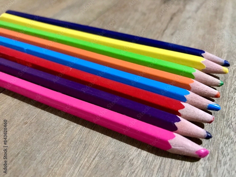 Fototapeta premium Bunch of fun mini colored pencils isolated on wood background. Multicolor group of cute small wooden pencils