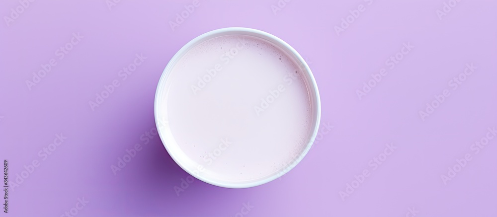 A white cup containing lavender moon milk is seen from a top view on a violet surface The image has copy space available A white cup containing lavender moon milk is seen from a top view on a violet surface The image has copy space available
