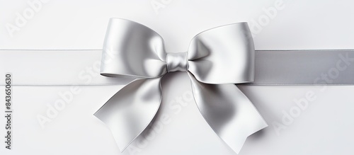 An elegant silver satin bow glistens on a pristine white backdrop leaving ample empty space for additional imagery
