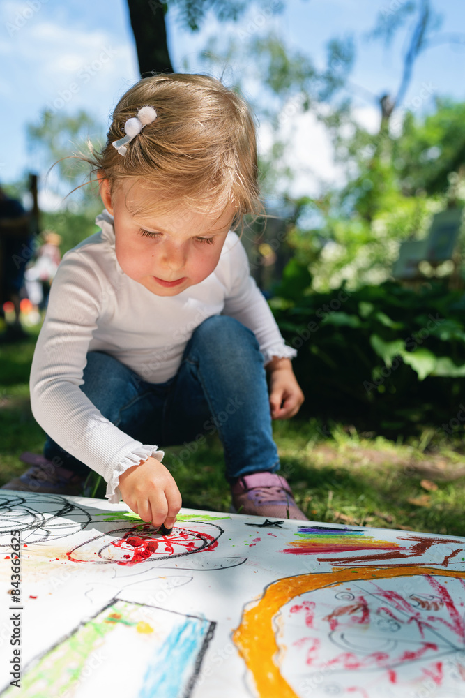 Girl painting outside. Happy child draws in the park. A little girl draws with crayons on paper in the park. Girl painting outside. Happy child draws in the park. A little girl draws with crayons on paper in the park.