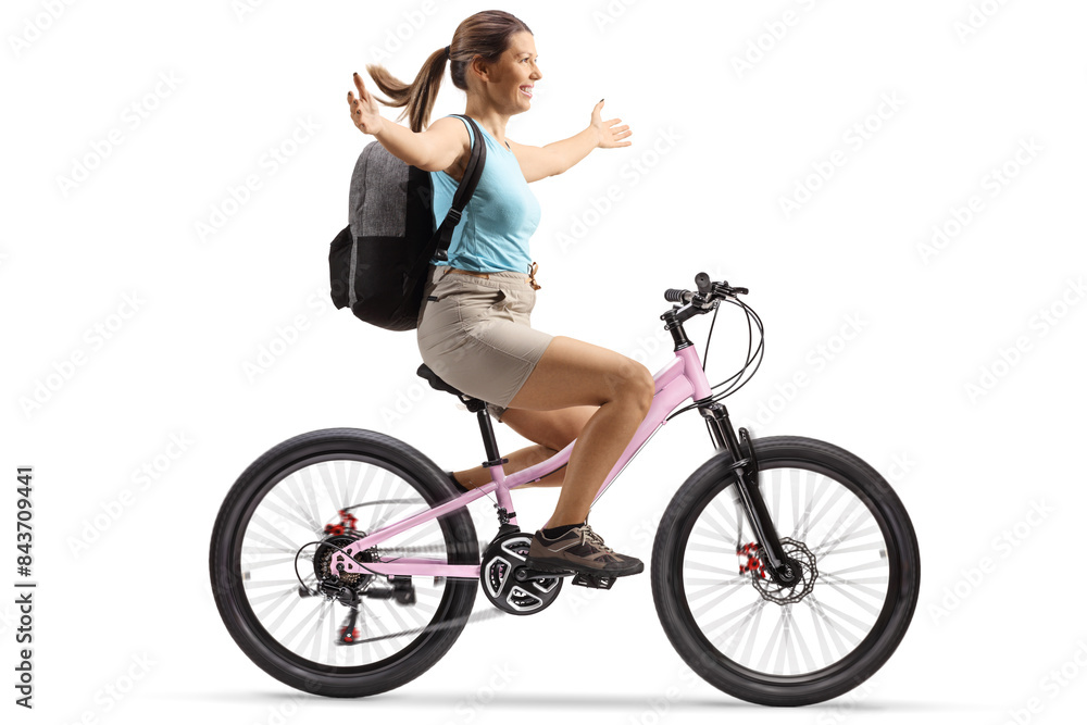 Full length profile shot of a woman with a backpack riding a bicycle and spreading arms Full length profile shot of a woman with a backpack riding a bicycle and spreading arms