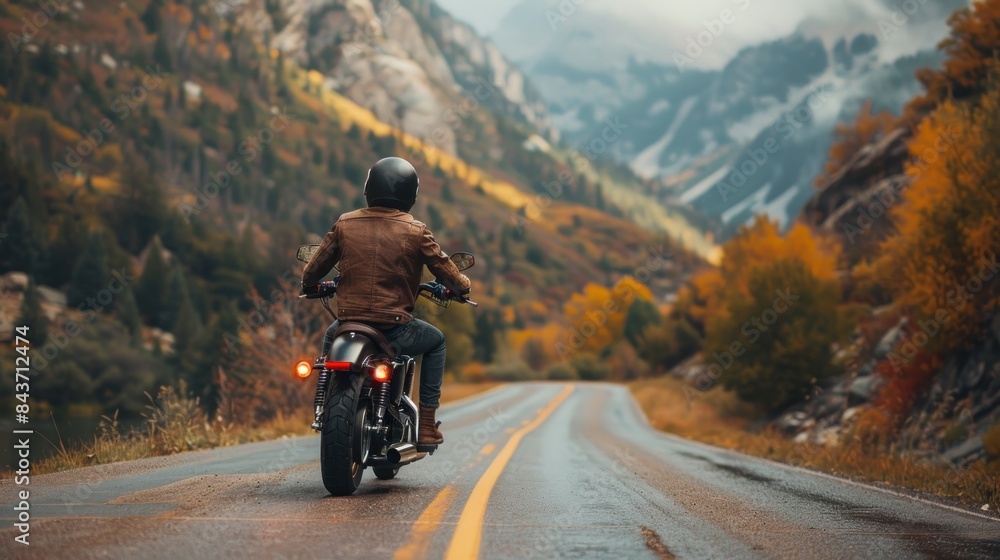 A man is riding a motorcycle down a road with mountains in the background A man is riding a motorcycle down a road with mountains in the background