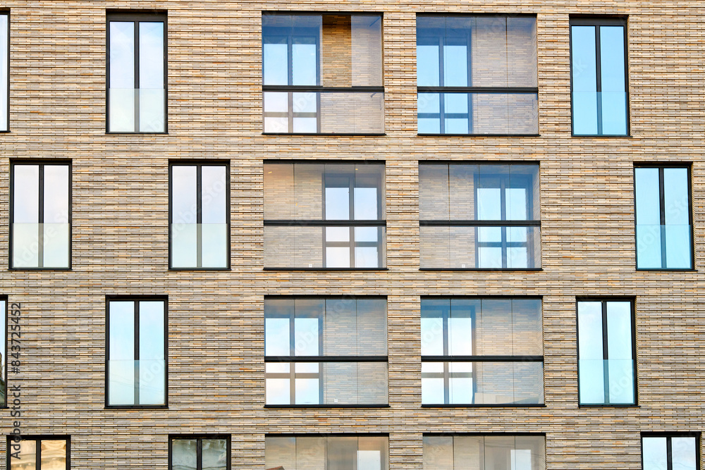 Modern residential building with large windows and clinker brick facade against susnet sky. Clinker brick facade and floor-to-ceiling glass windows. Modern residential building with large windows and clinker brick facade against susnet sky. Clinker brick facade and floor-to-ceiling glass windows.