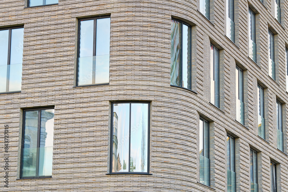 Panoramic glass windows on facade of modern residential building, clinker brick facade, architectural design, innovative use of materials. Clinker brick facade and floor-to-ceiling glass windows