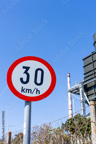 Speed limit sign near some industrial buildings