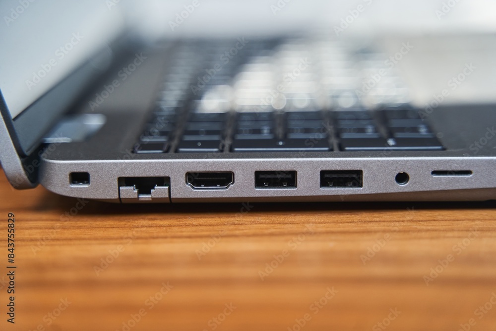 Side view of a gray laptop keyboard on a wooden table. USB ports on a laptop. High quality photo Side view of a gray laptop keyboard on a wooden table. USB ports on a laptop. High quality photo