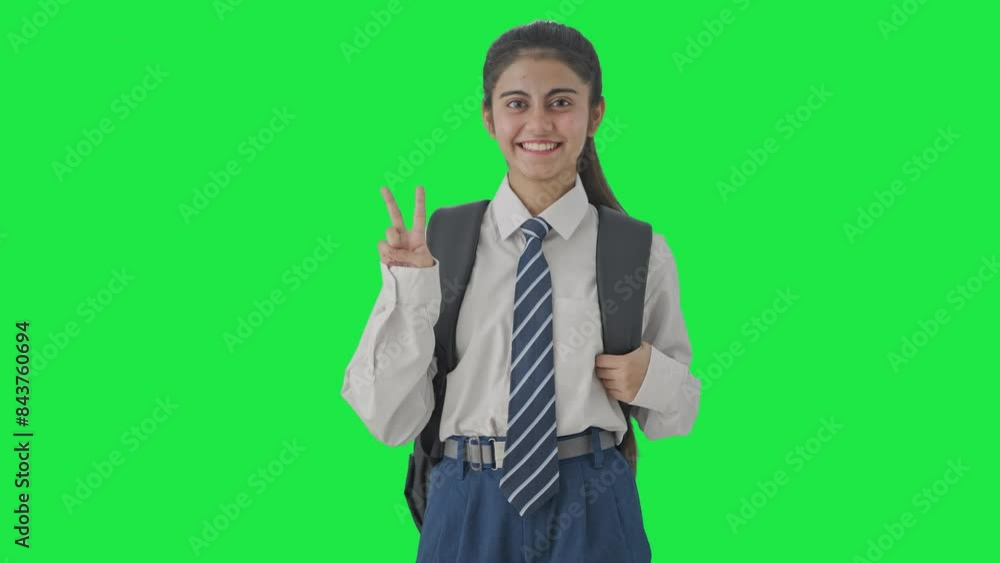 Happy Indian school girl showing victory sign Green screen Happy Indian school girl showing victory sign Green screen