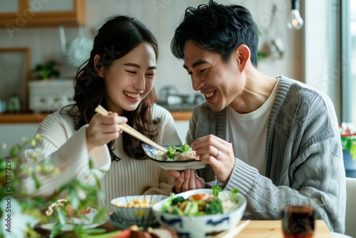 A japanese couple happily enjoying a meal together at home, white clean modern living room