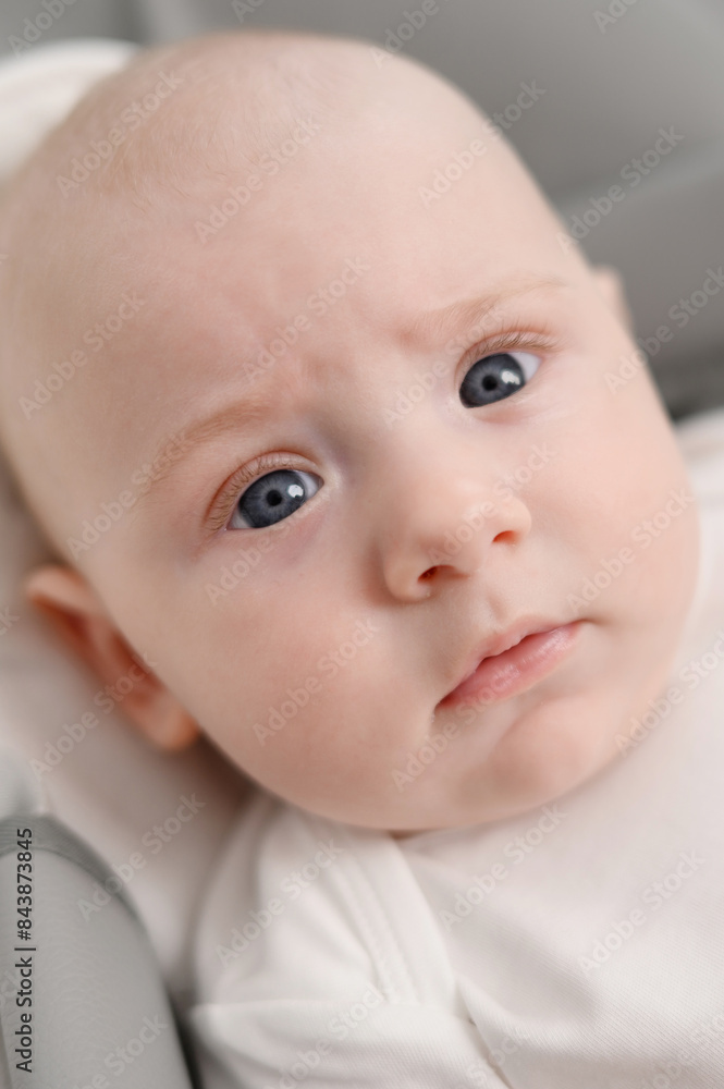 Close-up portrait of newborn baby. Serious face of infant. Concept of new birth, child care, development and growth of children. Vertical Close-up portrait of newborn baby. Serious face of infant. Concept of new birth, child care, development and growth of children. Vertical
