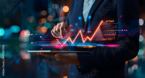 Man holding tablet with a holographic digital glowing rising arrow and stock market graph, depicting the financial growth of business or lipstick sales on a dark background