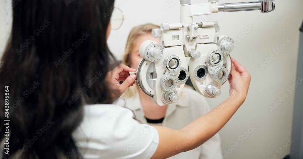 © N Lawrenson/peopleimages.com - Doctor, optometry and woman on phoropter for eye care, consultation or health exam in clinic. Ophthalmologist, test or patient on lens machine tool for vision check, wellness and eyesight correction