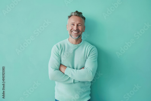 Mature man with blonde hair and approachable smile against a teal background © SerPak