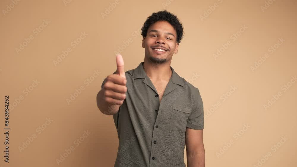 Smiling man making thumbs up gesture and nodding to show approval Smiling man making thumbs up gesture and nodding to show approval