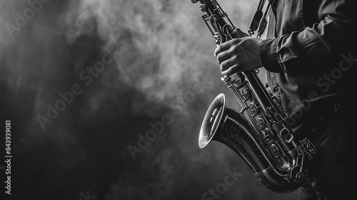 A man in a strict dark suit plays the saxophone. Black and white tinted photo.