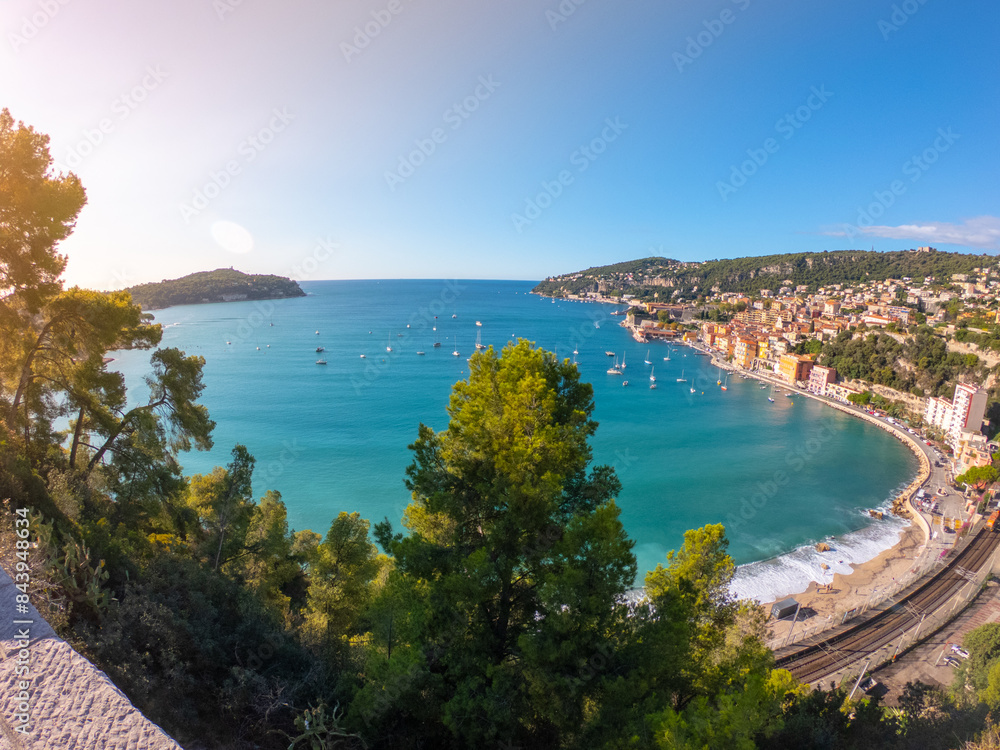 View of Port Villefranche-Santé with boats, catamarans, sails boats, speed boats, and yachts moored to the pier, during daytime with a clear blue sky, Villefranche-sur-Mer, France.