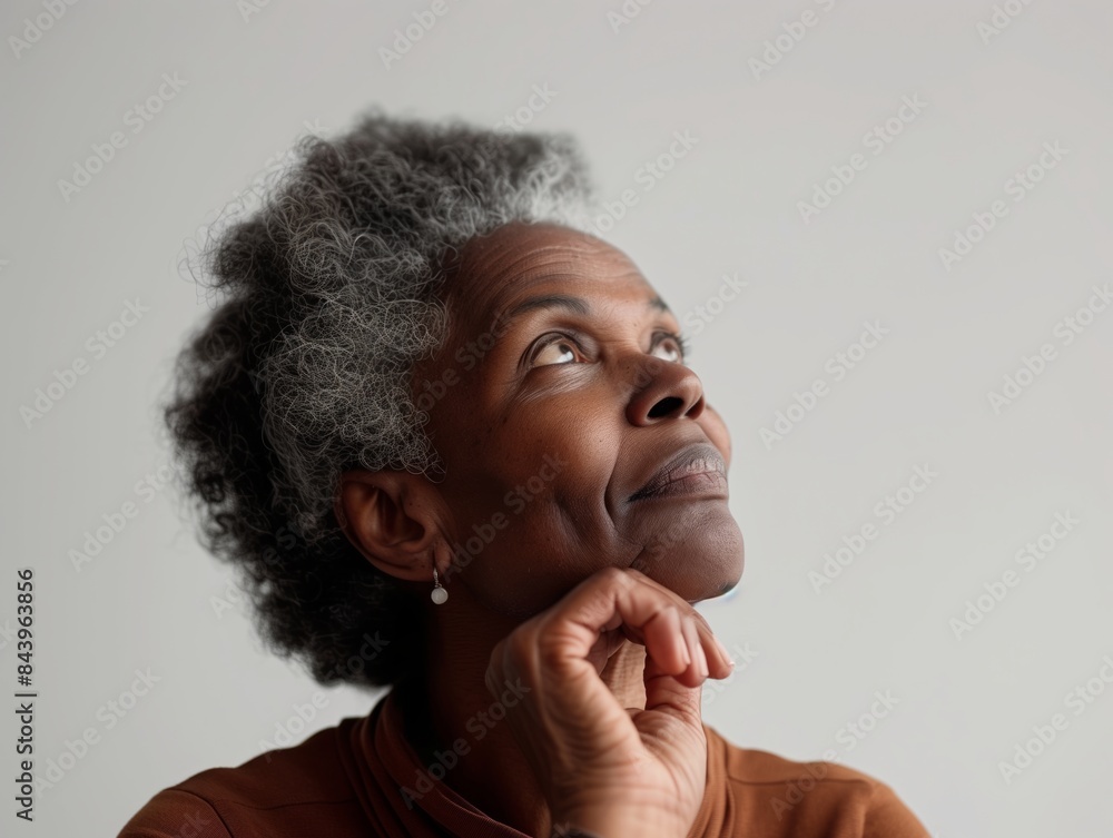 A woman with a gray head of hair is looking up at the sky. She is wearing a brown shirt and has a necklace around her neck. Concept of contemplation and reflection A woman with a gray head of hair is looking up at the sky. She is wearing a brown shirt and has a necklace around her neck. Concept of contemplation and reflection