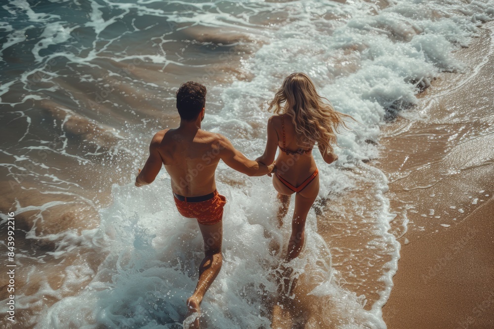 Fototapeta premium Couple Running Into Waves on Sandy Beach