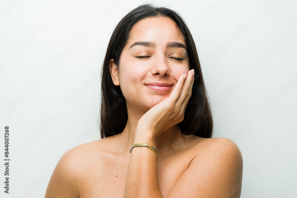 Beautiful young latin woman with flawless skin gently touching her face in a serene studio setting, showcasing a healthy skincare routine Beautiful young latin woman with flawless skin gently touching her face in a serene studio setting, showcasing a healthy skincare routine
