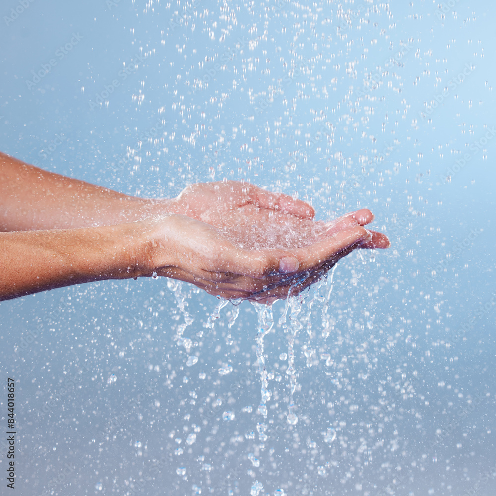 Person, hands and water for hygiene in studio, washing and grooming for skincare on blue background. Palms, cleaning and liquid for cosmetics or bacteria and germ protection, disinfect and hydration Person, hands and water for hygiene in studio, washing and grooming for skincare on blue background. Palms, cleaning and liquid for cosmetics or bacteria and germ protection, disinfect and hydration