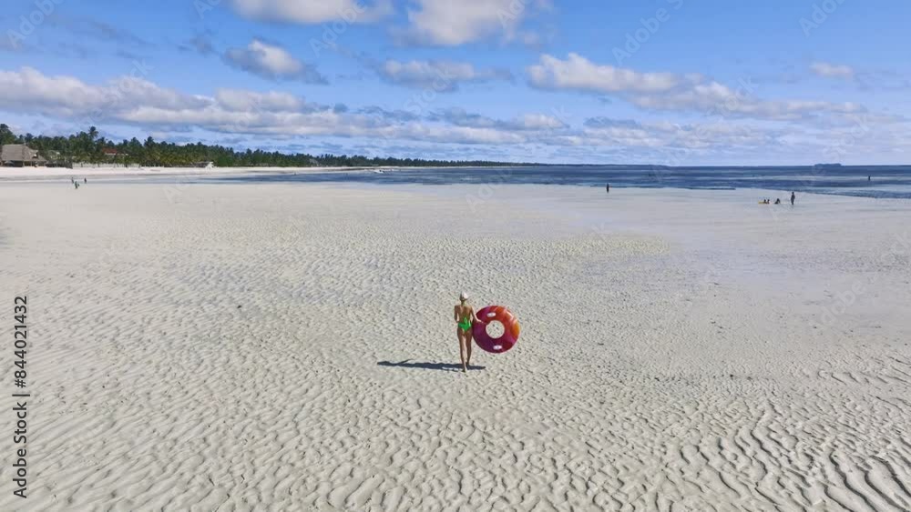 Aerial view of sporty slim woman with swimming ring, sandy beach, blue sea during low tide at sunny summer day in Zanzibar island. Top view of beautiful girl, sandbank, ocean, sky with clouds, palms Aerial view of sporty slim woman with swimming ring, sandy beach, blue sea during low tide at sunny summer day in Zanzibar island. Top view of beautiful girl, sandbank, ocean, sky with clouds, palms