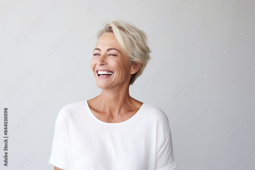Portrait of a happy mature woman laughing against a grey background. Portrait of a happy mature woman laughing against a grey background.