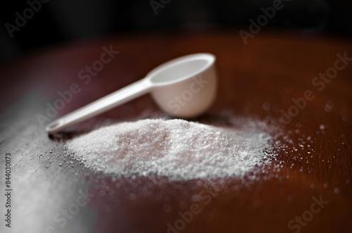 xylitol, sugar substitute, on a wooden surface with a plastic spoon (doser). photo