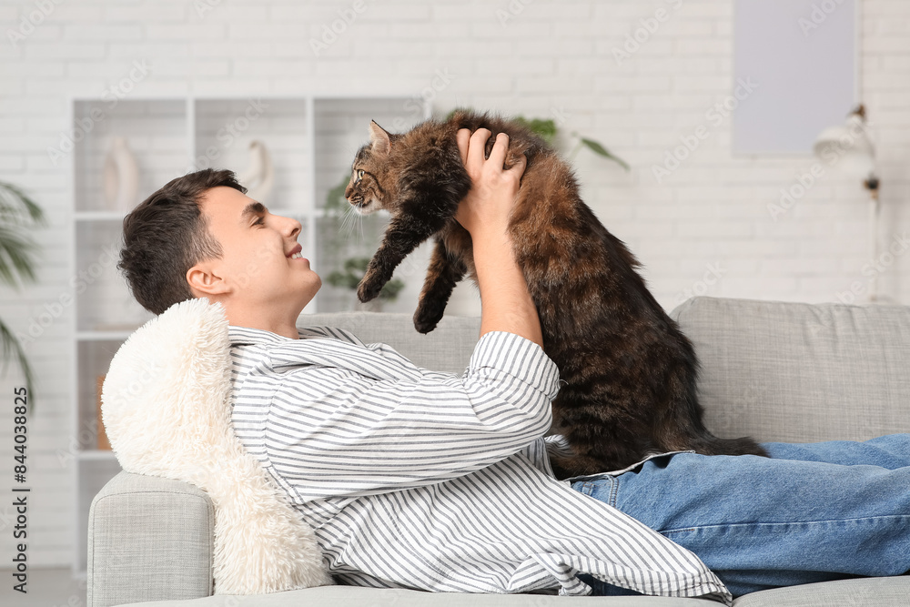 Young man with cute cat lying on sofa at home Young man with cute cat lying on sofa at home