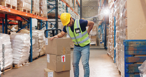 Back pain, man and boxes in warehouse for injury, overworked and strain with inventory. Logistics, male worker and backache in factory for export, commerce and packaging for trade or shipping