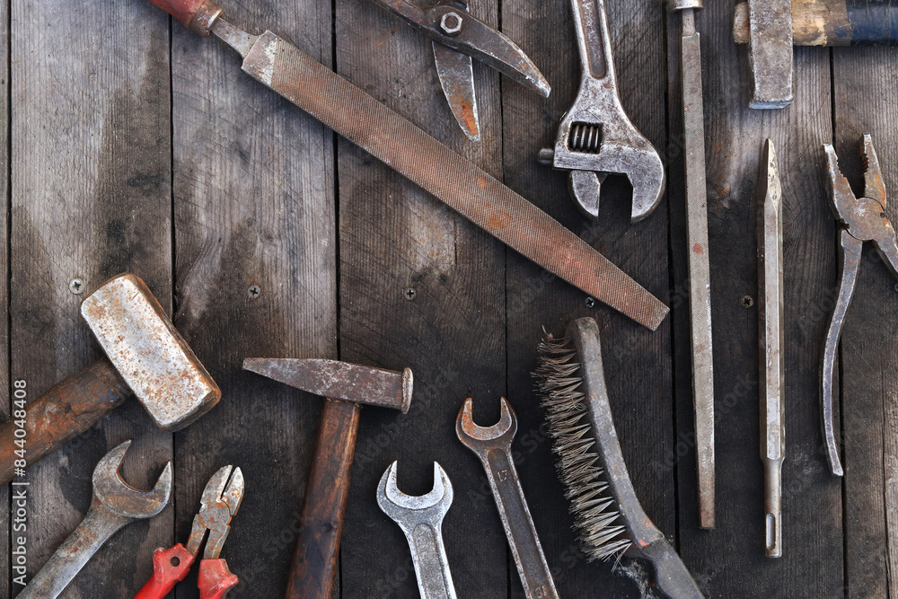 Old work tools on a plank wooden background, top view. Hammers, flat file, tin snips, brush, adjustable wrench and wrench. Hand tool. Builder's Day or Father's Day. Construction and renovation concept Old work tools on a plank wooden background, top view. Hammers, flat file, tin snips, brush, adjustable wrench and wrench. Hand tool. Builder's Day or Father's Day. Construction and renovation concept